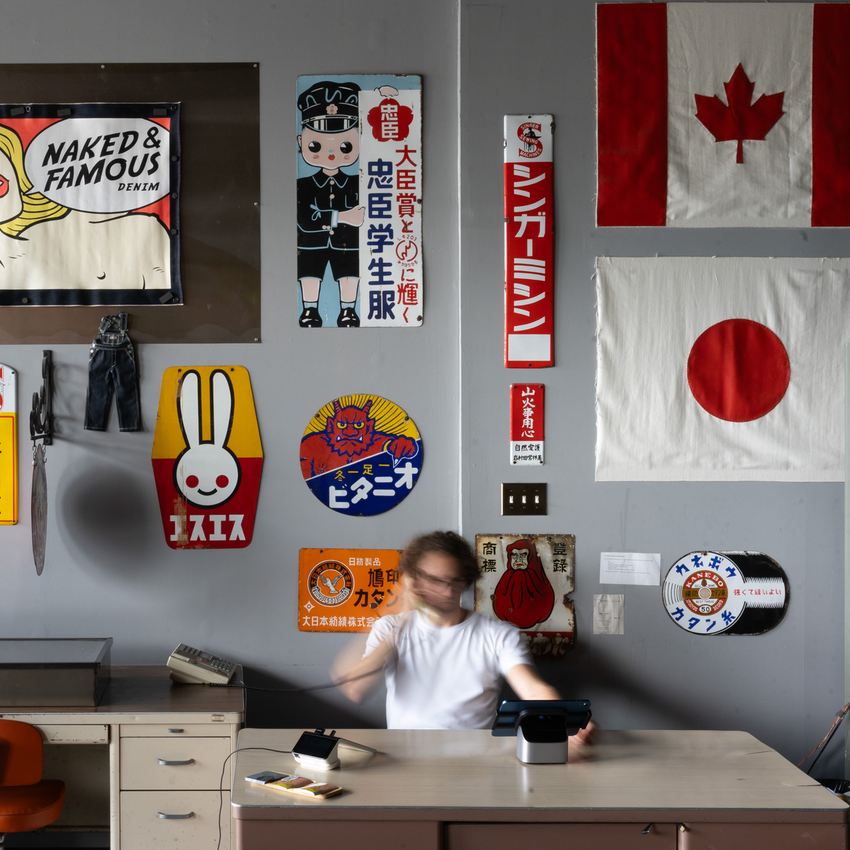 Person sitting at a desk in a room with various posters and flags on the wall.